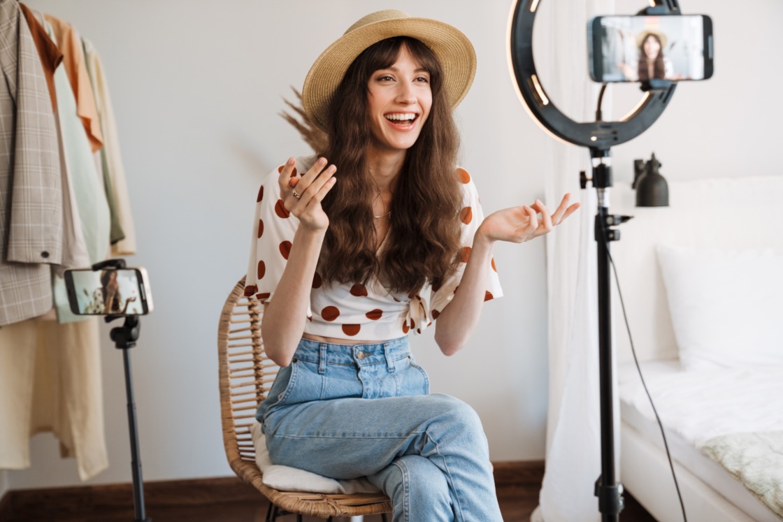 White woman smiling while taking selfie footage on cellphones UGC platforms: how to choose the right platform for your business
