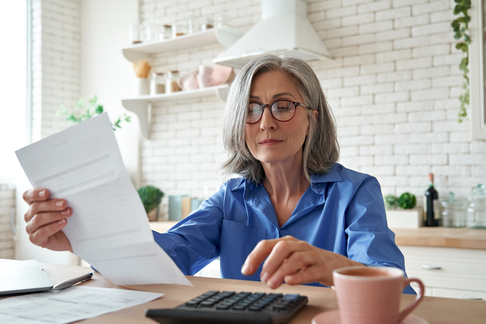 Dojrzała bizneswoman na freelancingu czyta, jak oszczędzać na emeryturę - zdjęcie poglądowe