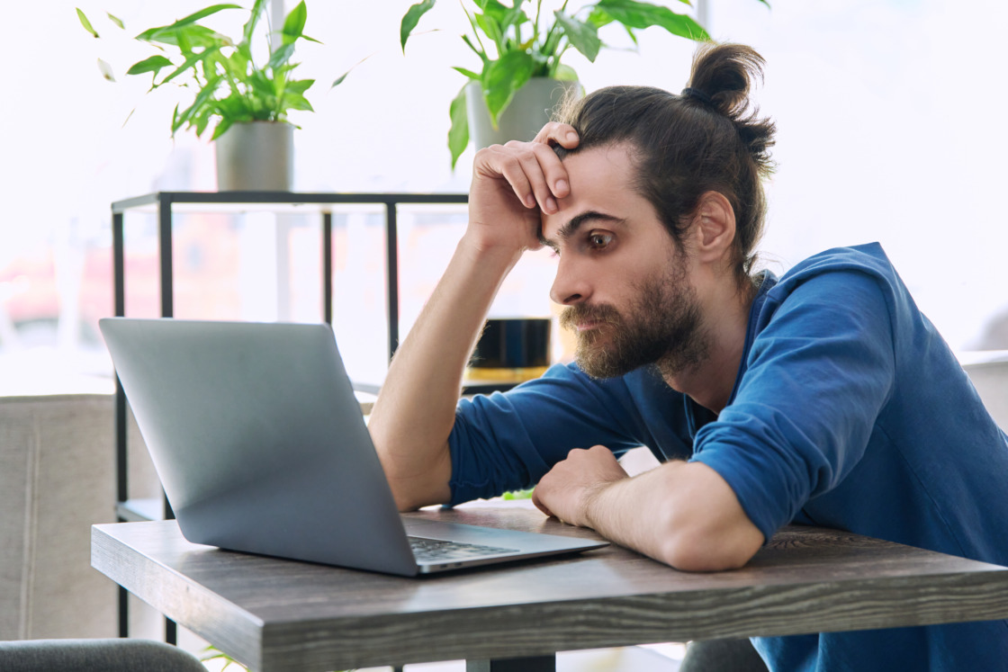 Ustawa platformowa uderza w IT, fintechy i e-commerce Freelancer przy laptopie zastanawia się, sprawdza, jak ustawa dla kurierów czyli ustawa platformowa wpłynie na IT, fintechy i e-commerce